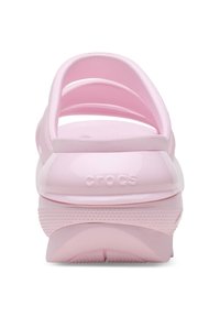 Różowe klapki Crocs z formowanym wkładem, trzema paskami i teksturowaną podeszwą. Nazwa marki widoczna jest na pięcie.