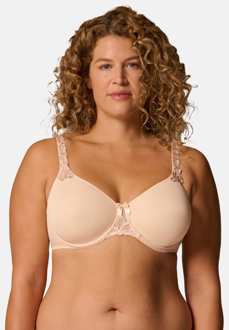 Beiger BH mit vorgeformten Körbchen und floralen Spitzenakzenten auf den Trägern. Verfügt über eine kleine Satinschleife in der Mitte und verstellbare Träger. Glatte Textur.