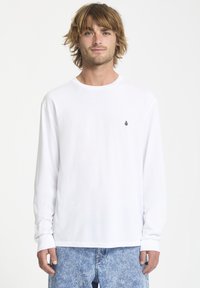 Weißes Langarm-T-Shirt mit Rundhalsausschnitt und kleinem schwarzem Logo auf der linken Brust. Der Stoff wirkt glatt und leicht.
