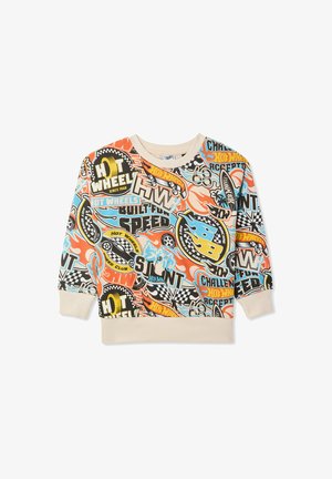Kolorowy sweatshirt z grafikami i tekstem na kremowym tle; zestawiony z jasnoniebieskimi spodniami i niebiesko-białymi trampkami.