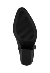 Suela de zapato negra con una superficie texturizada y un patrón geométrico; presenta una forma puntiaguda y un pequeño tacón cuadrado.