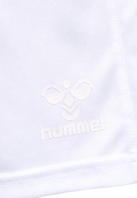 Tissu blanc en gros plan avec logo embossé hummel présentant un bourdon stylisé et le nom de la marque près de la couture cousue.