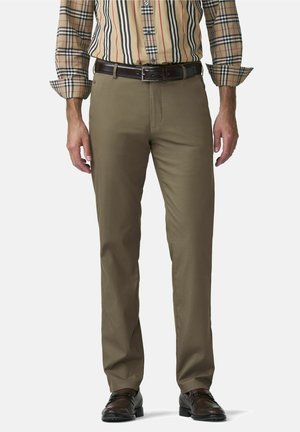 Mann trägt braune gerade geschnittene Hose, schwarzen Ledergürtel, braune Lederschuhe und ein beigefarbenes kariertes Hemd mit hochgekrempelten Ärmeln.