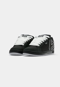 Schwarze Low-Top-Sneaker mit weißen Schnürsenkeln, mit dem Markennamen "etnies" auf der Zunge und der Seite, ausgestattet mit einem weißen Musterdesign im Fersenbereich.