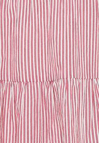 Bavlněné šaty s vertikálními pruhy v světle růžové a bílé barvě, s detailem na staženém pasu a texturovaným povrchem.