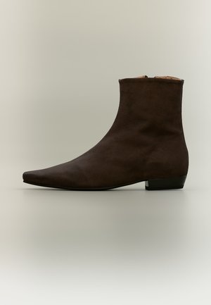 Dark brown suede ankle boot with pointed toe and low block heel on neutral background.
