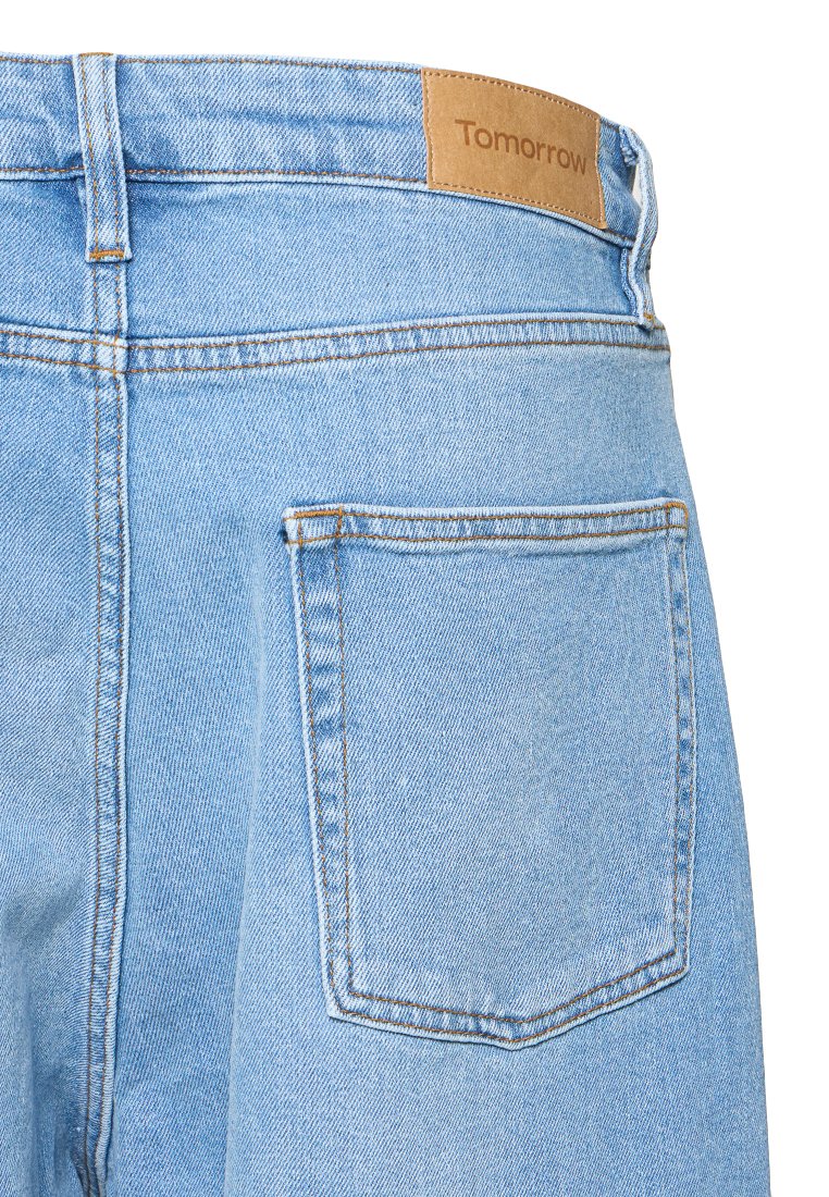Lichtblauwe denim jeans met een leren merklabel genaamd "Tomorrow," met een achterzak en contrasterende stikdetails.