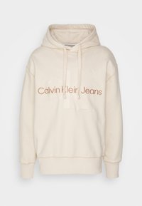 Felpa con cappuccio color crema realizzata in tessuto morbido. Presenta il logo ricamato "Calvin Klein Jeans" in marrone, con polsini e orlo a coste.