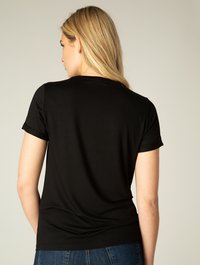 Zwarte t-shirt met korte mouwen, zichtbaar vanaf de achterkant, met een gladde textuur en een aansluitend ontwerp, gecombineerd met blauwe spijkerbroek.