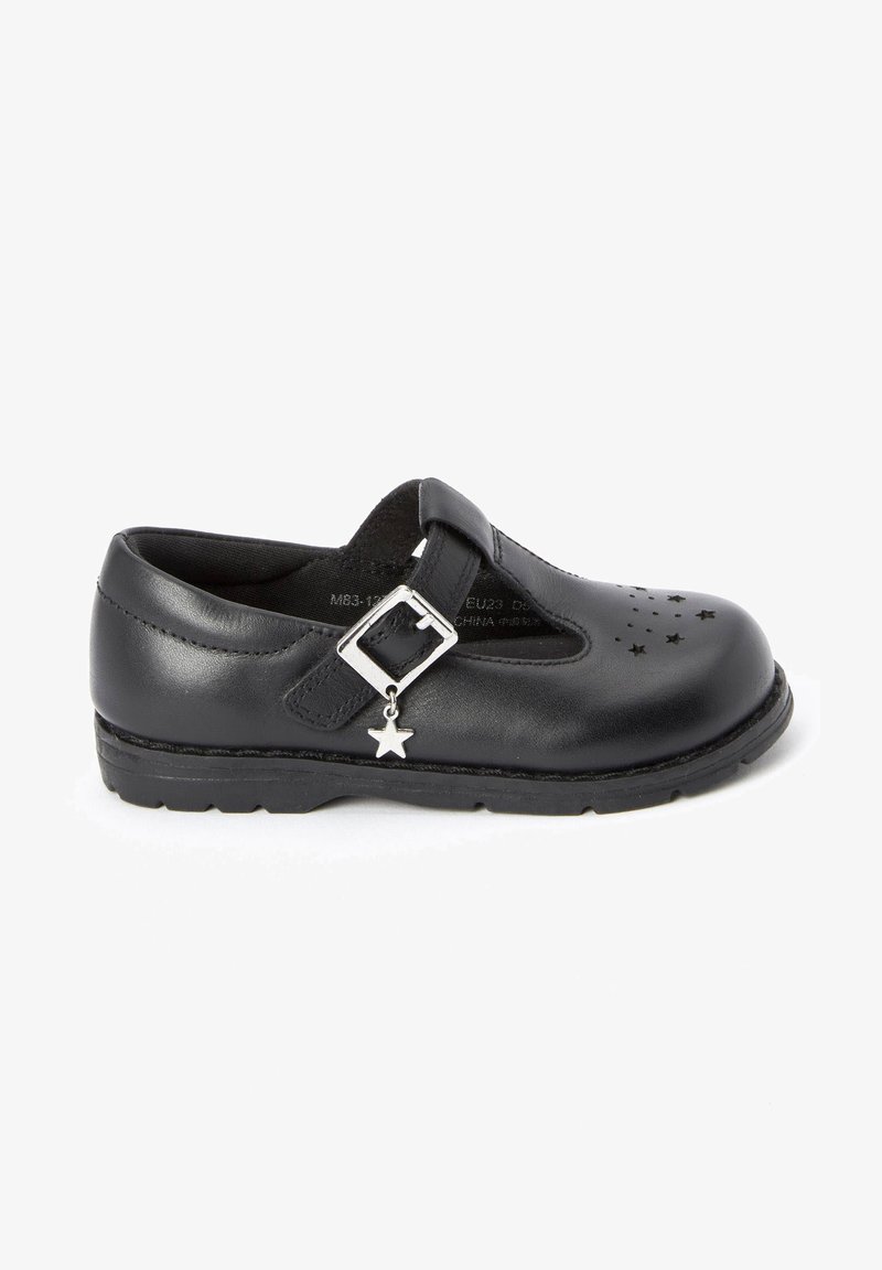 Schwarzer Lederschuh mit runder Zehe, Riemen und silbernem Sternanhänger, mit Stern-Ausschnitten im Obermaterial und einer strukturierten Gummisohle.