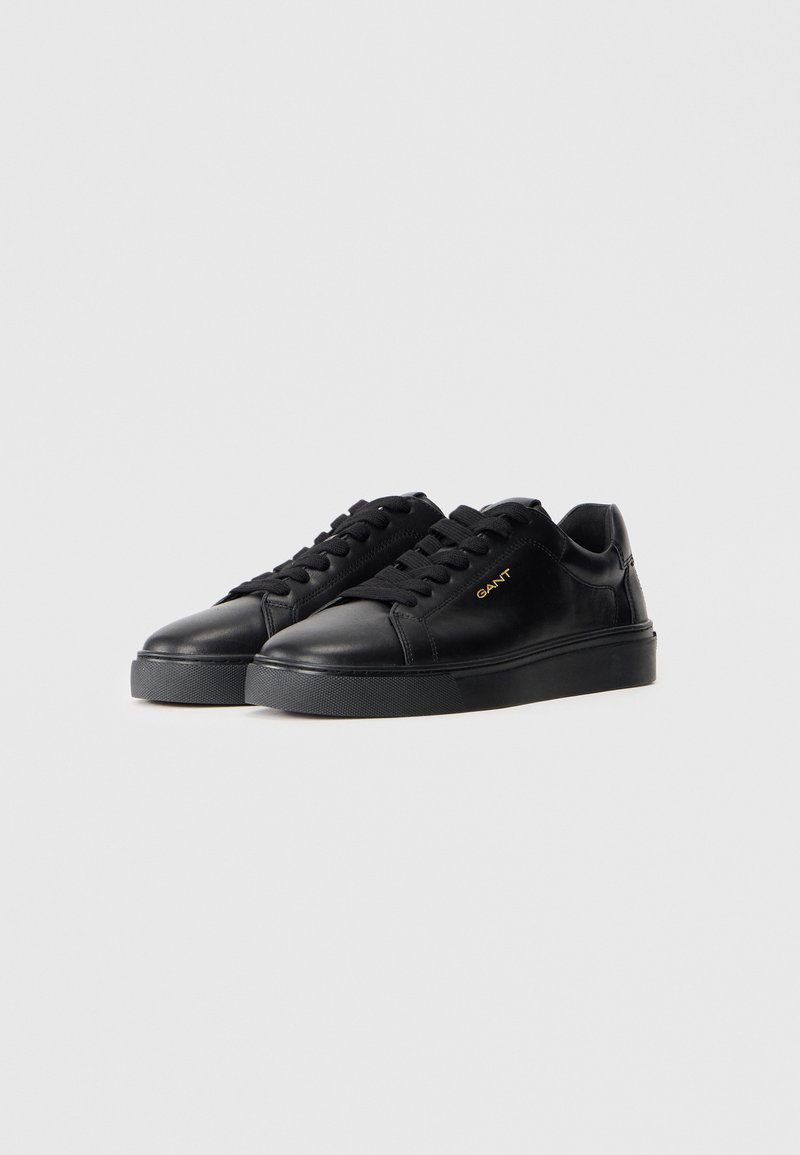 Czarne skórzane sneakersy o gładkim wykończeniu, zaokrąglonym nosku, z zapięciem na sznurówki i teksturowaną gumową podeszwą. Posiadają złoty akcent logo po boku.