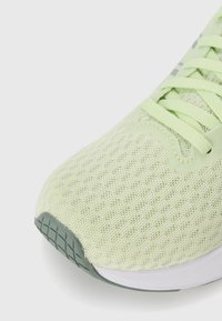 Világoszöld sportcipő, hálós felsőrésszel, texturált fűzőkkel, fehér középtalppal és texturált szürke outsole-lal.