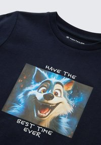 Granatowa koszulka z nadrukiem przedstawiającym uśmiechniętą twarz kreskówkowego wilka oraz tekstem: "MIEJ NAJLEPSZY CZAS W ŻYCIU" w kolorze białym. Materiał bawełniany.