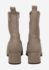 Bottines en suède beige à talon bloc, dotées d'une fermeture éclair, d'une texture lisse et de languettes à l'arrière pour un enfilage aisé.