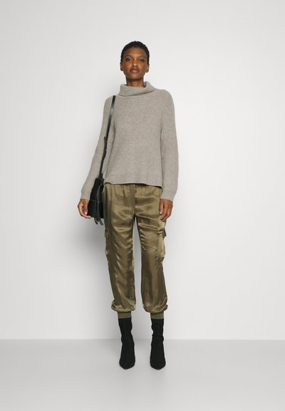 Light grey knitted sweater with a high collar; olive green satin cargo pants; black ankle boots; black shoulder bag. Clean, minimal backdrop.