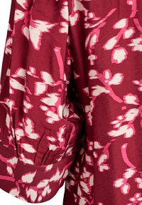 Viininpunainen paita, jossa on vaaleanpunainen kukkakuosi, täydentää poimittu hihansuupisto. Valmistettu pehmeästä kankaasta, jolla on sileä pintastruktuuri.