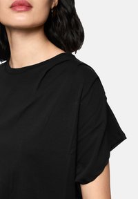 Black short-sleeve t-shirt made of soft fabric, featuring a round neckline and relaxed fit, with subtle texture and smooth finish.