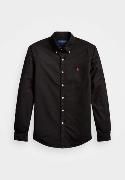 Camisa preta de mangas longas, com botões, feita de algodão e com colarinho clássico, apresentando botões brancos e um logotipo vermelho no lado esquerdo do peito.