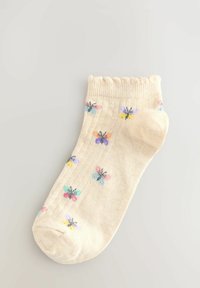 Beige ankelstrømpe med ribbet tekstur, featuring et spredt sommerfuglemønster i pastelfarver, og en bølget kant.