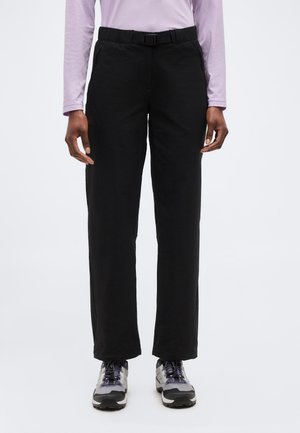 Άτομο που φοράει μαύρο παντελόνι ίσιας γραμμής με ενσωματωμένη ζώνη, ανοιχτό μοβ μακρυμάνικη μπλούζα και γκρι-μαύρα παπούτσια πεζοπορίας.