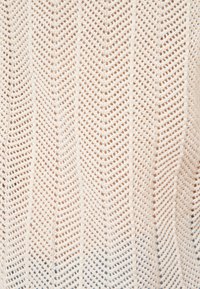 Cremefarbenes Strickgewebe mit Zickzackmuster und Struktur aus Lochstrick.