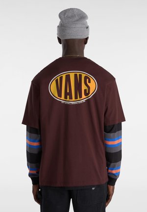 Burgundy t-shirt with a large yellow and black "VANS" logo on the back, layered over a long-sleeve shirt with multicolored stripes.