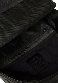 Mochila negra con bolsillo de malla, forro suave, compartimentos con cremallera y parche de cuero de marca. Exterior texturizado con costuras duraderas.