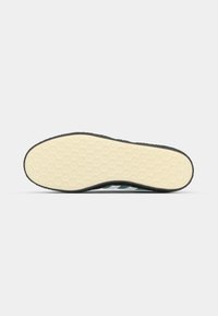 Talpa de pantof cu o suprafață din cauciuc crem texturat, având un model hexagonal și o margine neagră pentru aderență și durabilitate.