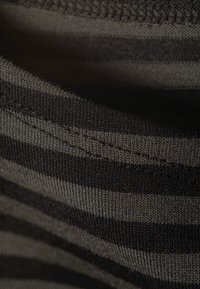 Černá a šedá pruhovaná látka s měkkou texturou. Detailní pohled ukazuje pletený vzor a prošívané okraje.