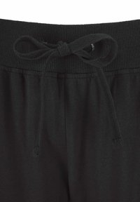 Black cotton joggers with a ribbed waistband, featuring a drawstring closure. The fabric is soft with a smooth texture, designed for comfort.