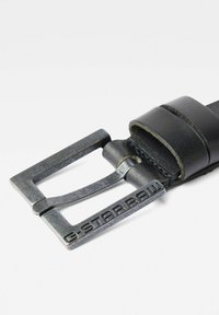 Cinturón de cuero negro con una superficie texturizada, con una hebilla metálica grabada con "G-STAR RAW." El diseño de la hebilla es rectangular con un pasador.