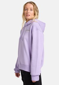 Sudadera de color púrpura claro con capucha, con puños y dobladillo acanalados, y un logo frontal en color contrastante. Tejido suave con un ajuste relajado.
