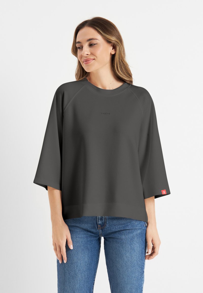 Donkergrijze oversized t-shirt met een ronde halslijn en raglan mouwen. Bevat een subtiele logo aan de voorkant en een rode label op de mouw.