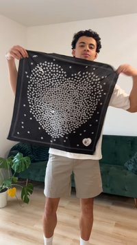 Černý šátek s motivem srdce tvořeným malými bílými puntíky, ohraničený bílou barvou. Lehká látka s hladkou texturou.