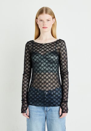 Schwarzes, transparentes Langarm-Oberteil mit einem Spitzenmuster und rundem Ausschnitt, über einem einfarbigen Camisole getragen, mit Daumenlöchern an den Ärmelsäumen.