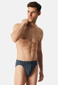 Marineblaue, gestreifte Badebriefer aus elastischem Material, mit tapered Design und bequemem Bund.