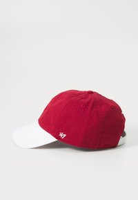 Rød bomullsbakset med hvit skjerm, med brodert logo på siden og strukturert stoff for grep. Standard form.