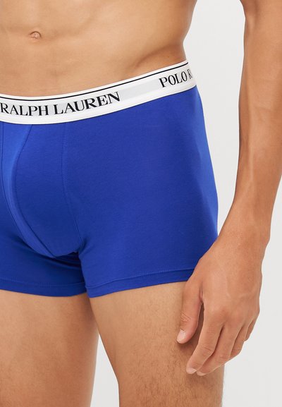 Kraljevsko plave bokserice od glatkog pamuka, s bijelim pojasom na kojem je crnim slovima ispisano "RALPH LAUREN" i "POLO". Prilagođeni kroj i srednji struk.