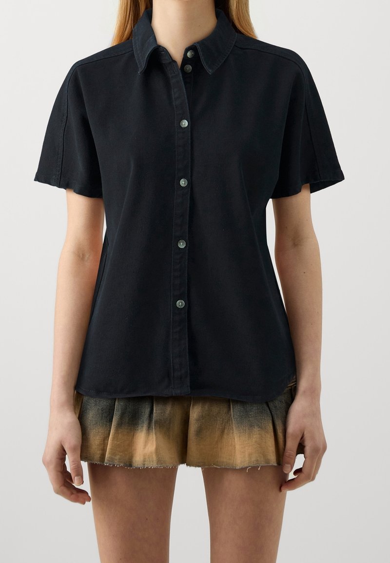 Camicia nera a maniche corte con bottoni, realizzata in cotone e dotata di colletto, con bottoni frontali e una vestibilità rilassata. Nessun motivo o accento notevole.