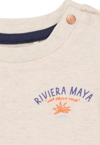 Lichtbeige katoenen T-shirt met een marineblauwe halslijn, voorzien van de slogan "RIVIERA MAYA" en een bloemenafbeelding in oranje en blauw, afgemaakt met een drukknoopje.