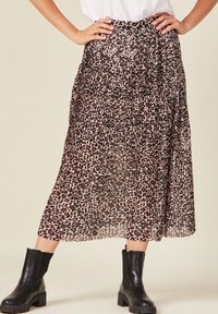 Gonna maxi plissettata in un tessuto trasparente con un motivo a stampa leopardata nei toni del marrone e del nero, abbinata a stivaletti neri.