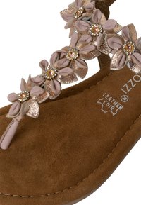Brune semsket sandal med en thong-rem prydet med tre teksturerte blomster med metallisk aksent, hver med en sentral edelsten.