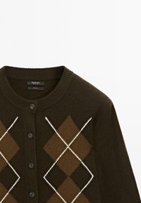 Brauner Wollcardigan mit einem Rautenmuster in hellbraun und weiß, mit einem gerippten Kragen und drei schwarzen Knöpfen.
