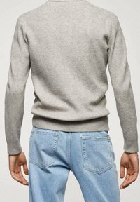 Šedý žebrovaný svetr s dlouhými rukávy, přiléhající v pase. V kombinaci se světle modrými džínami s klasickými kapsami a volným střihem.