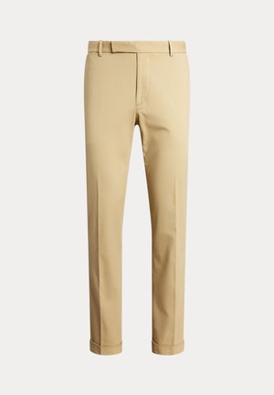 Pantalon beige pour homme taillé sur mesure avec passants de ceinture et ourlets retroussés, présenté sur un fond clair uni.