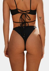 Czarny bikini o fakturowanym wykończeniu, z krzyżującym się tyłem i regulowanymi sznurkami, z wysokimi majtkami ozdobionymi złotymi akcentami.