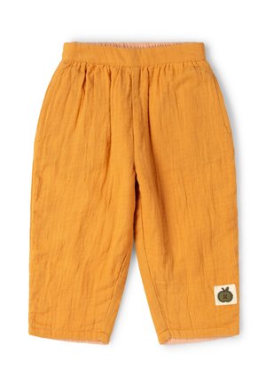 Loose-fit mustard yellow cotton pants with elastic waist and a small green apple patch near the bottom hem on the right leg.