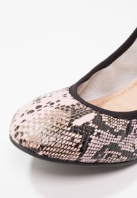 Chaussure plate avec bout arrondi, motif peau de serpent rose et noir, et bordure noire autour de l'ouverture.