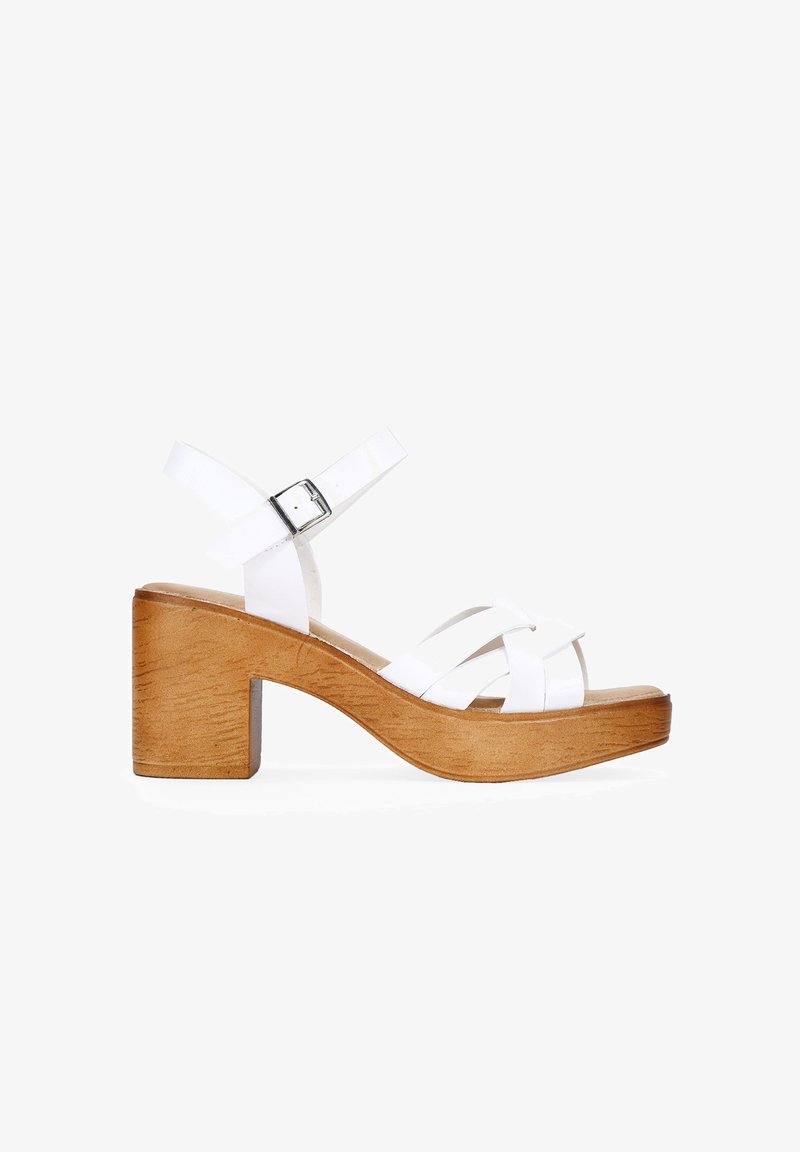 White leather heeled sandals featuring a wooden block heel, crisscross straps, and an adjustable ankle buckle. Smooth texture, open toe design.