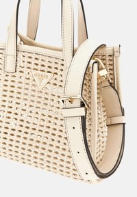 Borsa a tracolla beige intrecciata con doppi manici e tracolla regolabile. Caratterizzata da un logo triangolare dorato e dettagli neri sulla tracolla.